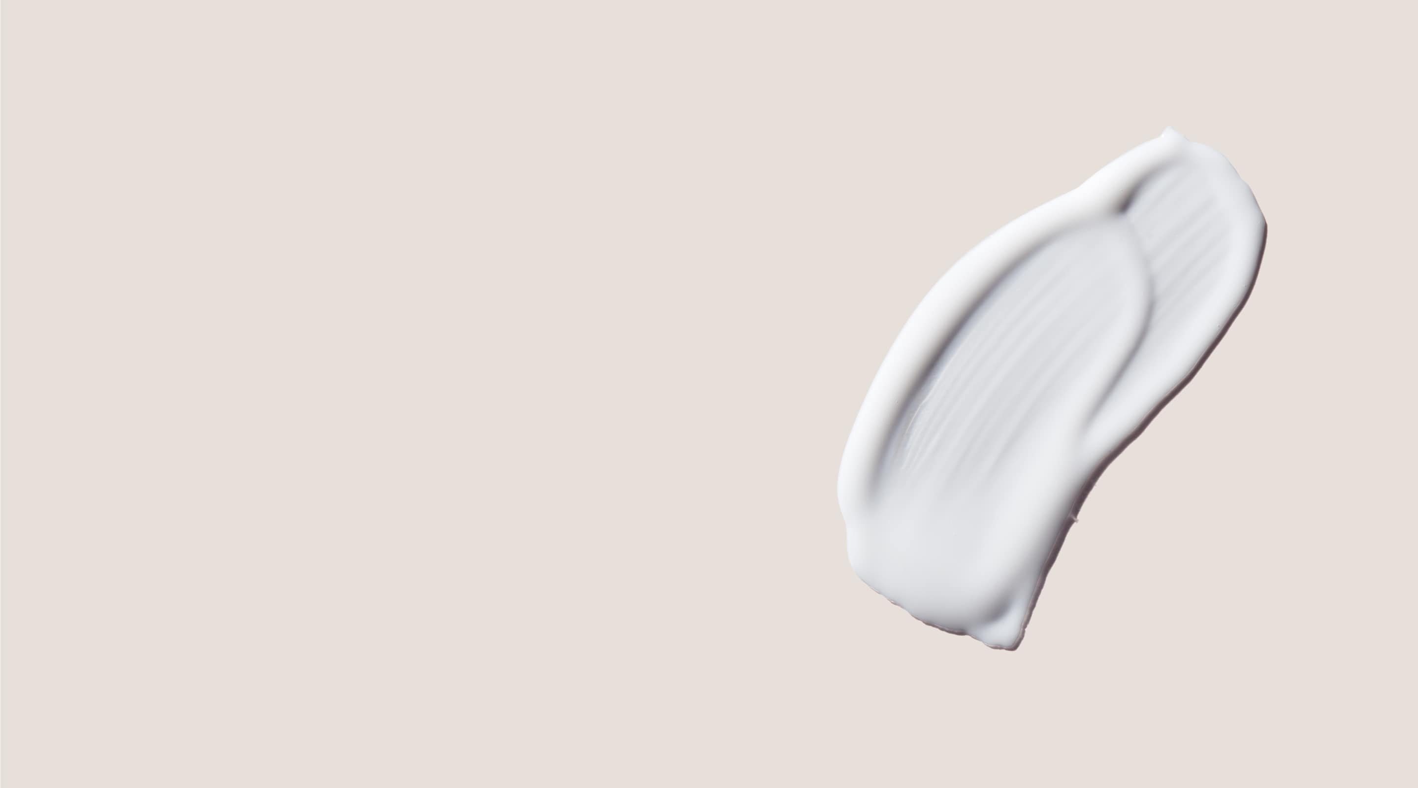 An aesthetic dallop of white Vella serum on a beige background